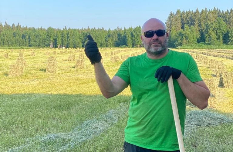 Mies esittelee ylpeänä heinäpeltoaan.